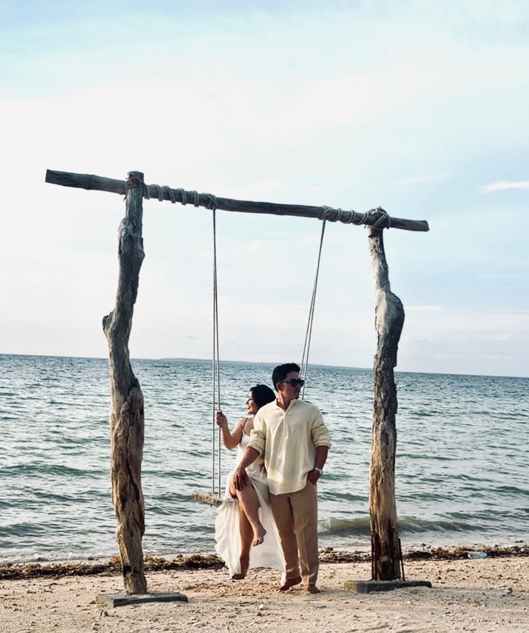 Mark and Lomi together on a wooden beach swing by the sea